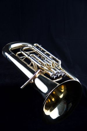 A gold brass bass tuba euphonium isolated on a black background in the vertical format with  copy space.の写真素材