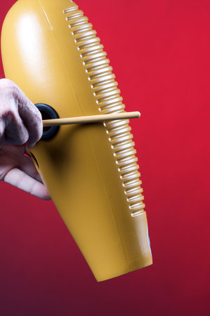 A guiro gourd percussion instrument being played against a red background in the vertical format with copy space.の写真素材