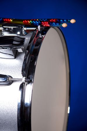 A silver sparkle snare drum with colorful sticks isolated against blue background in vertical format.の写真素材