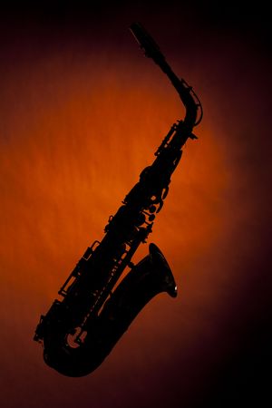 An alto saxophone silhouette isolated against a spotlight gold background in the horizontal view with copy spaceの写真素材