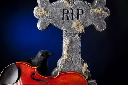 A Halloween violin viola with a blackbird crow and gravestone against a dark blue spotlight background.の写真素材