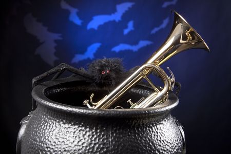 A gold brass Halloween trumpet in a witch pot and bats against a dark blue background.の写真素材