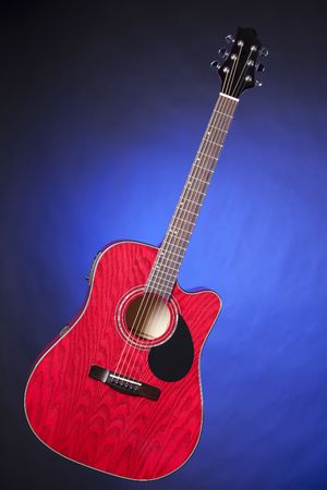 A red acoustic electric guitar  isolated against a blue spotlight background in the vertical format.の写真素材