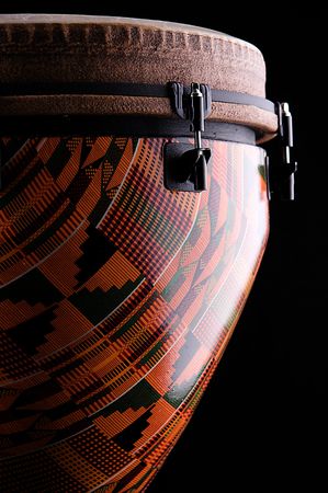 An orange African or Latin Djembe conga drum isolated on black background in the vertical forの写真素材