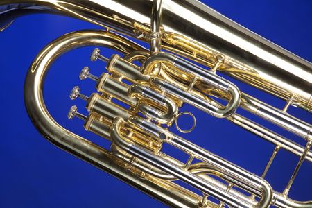 A gold brass tuba euphonium baritone horn isolated against a blue background in the horizontal format.の写真素材