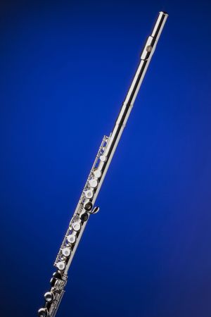 A silver flute isolated against a spotlight blue background in the vertical format.の写真素材