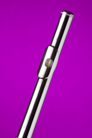 A silver flute head joint isolated against a bright pink background in the vertical format.の写真素材