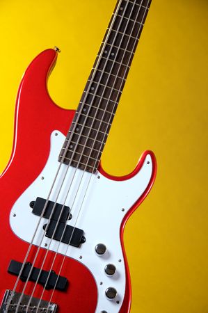 A metallic red electric guitar isolated against a yellow background in the vertical format.の写真素材
