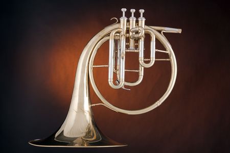 A gold antique peck-horn or French horn isolated against a spotlight gold background.の写真素材