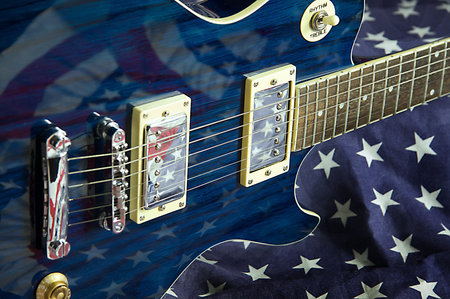 A blue wood electric guitar shot on an American flag background in the horizontal format.