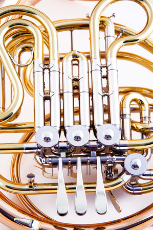 A brass and copper French horn isolated against a white background close up in the vertical format.