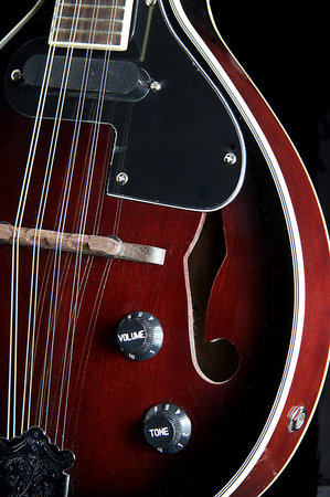 A red mandolin isolated against a black background in the vertical format.