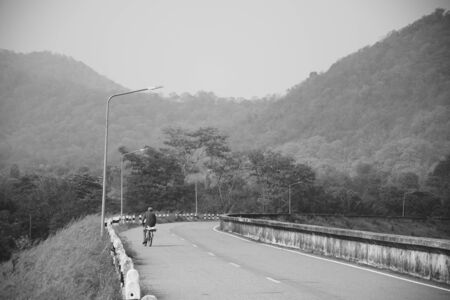 The man  is riding bicycle on the road with mountain backgroundの写真素材