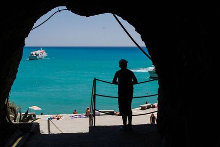 Figure in the shade - view of the beach and bay - Monterosso Al Mare, Liguria, Italyの写真素材