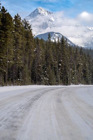 Bow Valley Parkway road covered in ice and snow with Cascade Mountain in background during winter in...