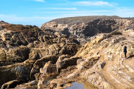 Active senior woman stands on the slippery rocks of Point Lobos State Reserve in California, admiring the sceneryの写真素材
