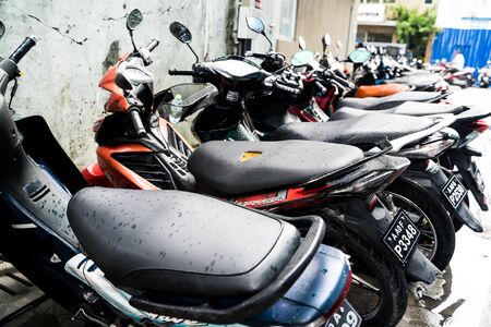 Male, Maldives - November 26, 2019: Row of motorbikes or motorcycles, parked along the side of a road. This is the main mode of transportation on the Maldivian islandの写真素材