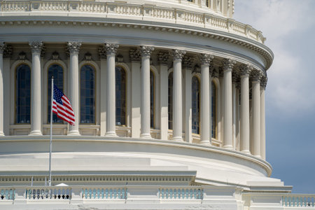Close up view of the US Capitol Building dome and columns, with the American Flag