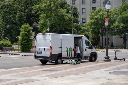 Washington, DC - August 4, 2019: A van with a Lime scooter charger, known as a Juicer, places the dockless scooters on the sidewalk, fully charged for useのeditorial素材