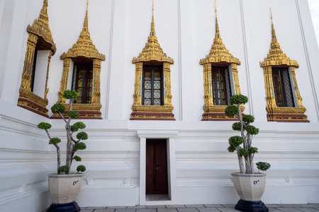 Detailed and ornate window views of temple at the Grand Palace in Bangkok Thailand, with potted plantsのeditorial素材