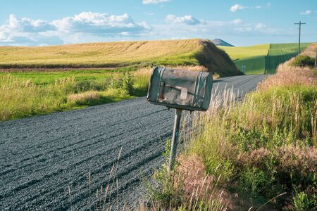 Old rusted abandoned mailbox by the side of a dirt unpaved farm road in the Palouse of Eastern Washington Stateの写真素材