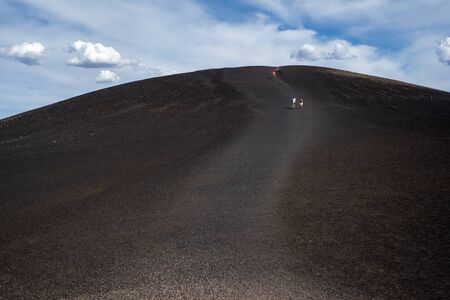 Hikers walk down from the Inferno Cone at Craters of the Moon National Monumentの写真素材