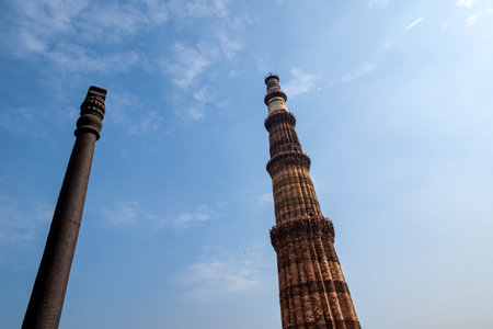 Famous Iron Pillar with the Qutub Minar minaret columb in New Delhi, India, located In the courtyard...