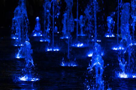 Abstract view of blue light up water fountains dancing at nightの写真素材