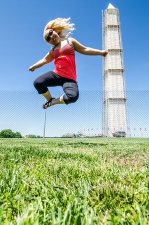 Blonde woman (20s) jumps in front of the Washington Monument. Concept for freedom and independenceの写真素材