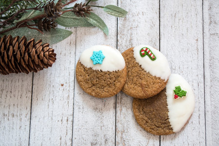 Ginger Snap Christmas cookies dipped in white chocolate, isolated on a wooden background with pine...