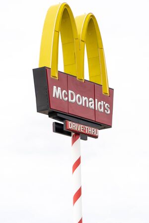 AUGUST 12 2018 - NORTH POLE, ALASKA: Artistic angle of a McDonalds sign and a tree Signpost is decorated like a candy cane to adhere to the Christmas theme of the townのeditorial素材