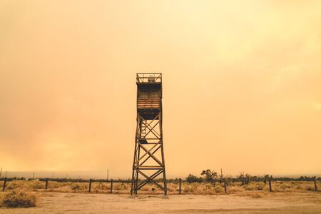 Guard Tower at the Manzanar Japanese Internment Camp in Independence California, during a smokey wildfire, bringing orange haze to the skyのeditorial素材