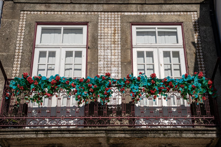 Cute window with tile facade and red flowers on an ornate balcony in Porto, Portugalの写真素材