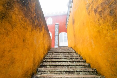 Sintra, Portugal - January 18, 2020: Extremely heavy, thick fog at the colorful Pena Palace in the winter. View of the steep steps with red and yellow wallsのeditorial素材
