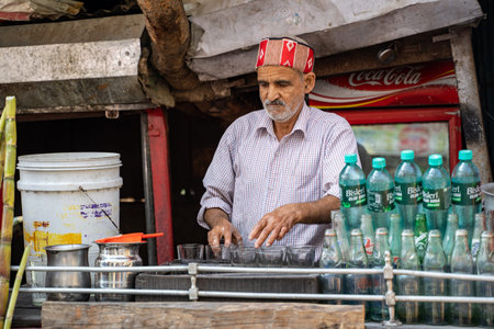 Rishikesh, India - Feburay 22, 2020: Indian man prepares glasses to make homemade sugarcane juice at...
