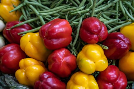 Colorful red and yellow peppers with peas in the backgroundの写真素材