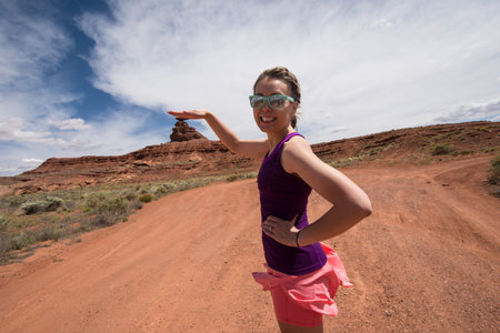 An adult female shows a forced perspective view of Mexican Hat rock formation in the Utah desert by...
