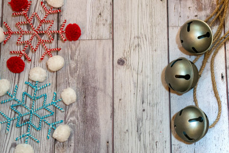 Bakers twine fabric snowflakes and large jingle bells flatlay on wood background. Useful for...