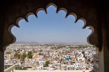 Udaipur, India - March 14, 2020: Aerial view of the Udaipur Cityscape in the state of Rajasthan. Framed by an archway of City Palaceの写真素材