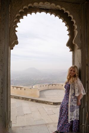 Woman tourist stands at an arched doorway, posing at the Monsoon Palace in Udaipur, Indiaの写真素材