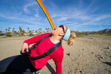Rainbow made of rebar materials in the desert on a sunny day, while woman attempts to taste and eat...