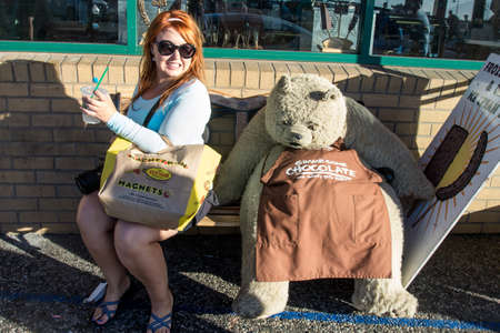 JULY 7 2017 - SAN FRANCISCO, CALIFORNIA: An adult female tourist looks in disgust at a Rocky Mountain Chocolate bear mascot, "Truffles", outside of the Fisherman's Wharf candy store.のeditorial素材