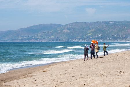 Malibu, California - March 26, 2019: Adult tourists take selfies and photos, posing with umbrella props while enjoying the sunshine at Point Dume beachのeditorial素材