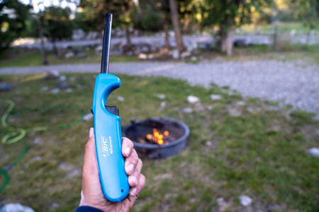 Livingston, Montana - July 3, 2020: Hand holds up a Bic Multipurpose lighter, with a campfire...