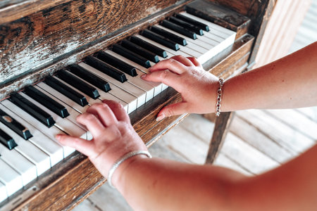 Female plays an old rustic piano, only arms and fingers shown. Selective focus on right hand