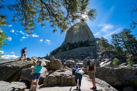 Wyoming, USA - June 23, 2020: Tourist hikers walk towards Devils Tower National Monument in the morning, taking photos and selfies, goofing off on the rocksのeditorial素材