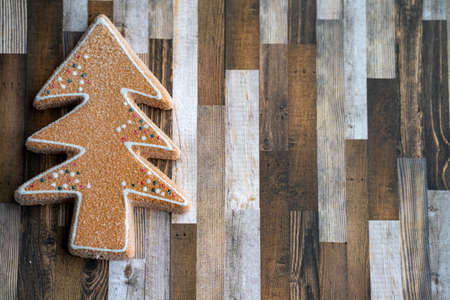 Sugary gingerbread cookie tree on a wood plank background, useful for Christmas holiday projectsの写真素材