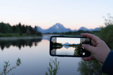 Wyoming, USA - June 28, 2021: Oxbow Bend in Grand Teton National Park at sunrise. Tourist taking a photo with a phoneのeditorial素材