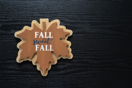 Maple leaf with Fall Sweet Fall printed on it, on a black wooden background for autumn projectsの写真素材
