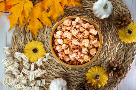 Flat lay for autumn, with bowl of flavored popcorn, surrounded by pumpkins, sunflowers, maple leaves...